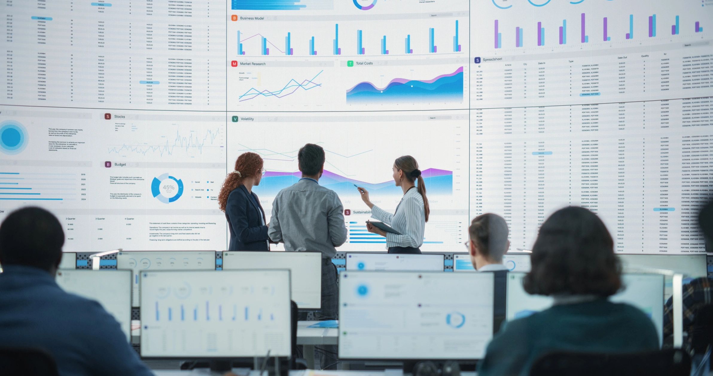 Team of data professionals reviewing dashboards on a large screen